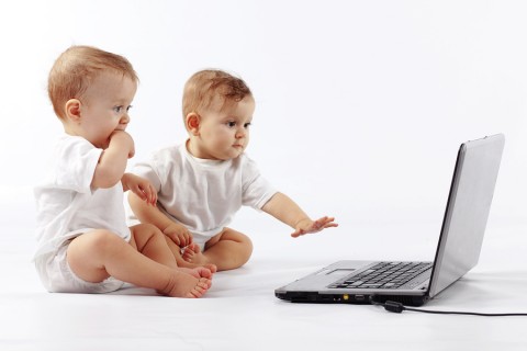 Two cute babies playing with laptop