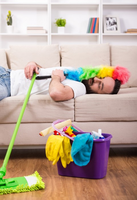 Man is tired and sleeping on sofa during cleaning at home.